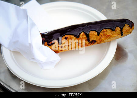 Eine einzelne Schokolade Eclair auf einem weißen Teller Stockfoto