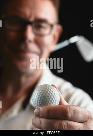 Nahaufnahme, reifer Mann Golfer tragen ein weißes Hemd und er hält einen Golfball auf Seite Eisen Golfclub auf seiner Schulter - Fokus auf ba Stockfoto