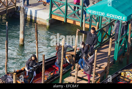 Gondoliere helfen Touristen an Bord eine Gondel in Venedig Lagune Veneto Italien Europa Stockfoto