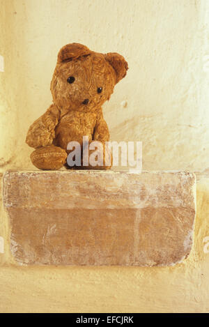 Vintage Teddybär sitzend auf steinernen Sims schauen traurig, als ob gefangen oder vergessen Stockfoto