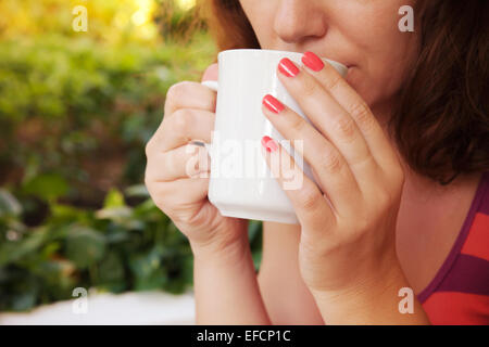 Frau hält weiße Tasse Kaffee in ihren Händen. Nahaufnahme Outdoor-Foto Stockfoto