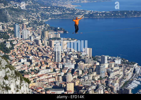Junger Mann, der in einer Höhe von 550 Metern über dem Meeresspiegel Slacklining (Slacklining) anführt. Fürstentum Monaco in der Ferne. La Turbie, Frankreich. Stockfoto