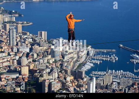 Junger Mann, der in einer Höhe von 550 Metern über dem Meeresspiegel Slacklining (Slacklining) anführt. Fürstentum Monaco in der Ferne. La Turbie, Frankreich. Stockfoto