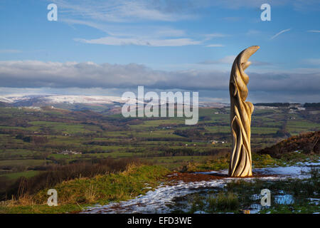 Skulptur auf Jeffreys Hill in der Nähe von Longridge in Lancashire, Preston, Großbritannien Winterwetter im Januar. Der Sonnenfänger von Halima Cassell hat eine geschnitzte Holzstatue mit Wahrzeichen geschnitzt, die auf das Vale of Chipping und die Fjells des Forest of Bowland blickt. Der Stamm einer 150 Jahre alten Eiche wurde in einer Serie von vier temporären Künstleraufträgen für ambitionierte Arbeiten in der Landschaft verwendet, die auf einige der beliebtesten Orte rund um den Forest of Bowland reagieren. Die Kommissionen sind Teil von Bowland Revealed und feiern 50 Jahre Forest of Bowland als ein Gebiet von herausragender natürlicher Schönheit. Stockfoto