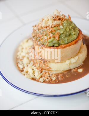 Pieminister Kuchen serviert mit Kartoffelpüree, Erbsenpüree, Zwiebeln und Käse in St Nicks Markt, Bristol. Stockfoto