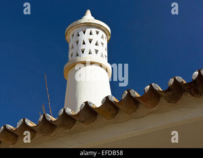 Einen einzigen Schornstein vor einem tiefblauen Himmel in Olhos de Agua, Portugal. Ein Terrakottafliesen Dachkante kann gesehen werden. Stockfoto