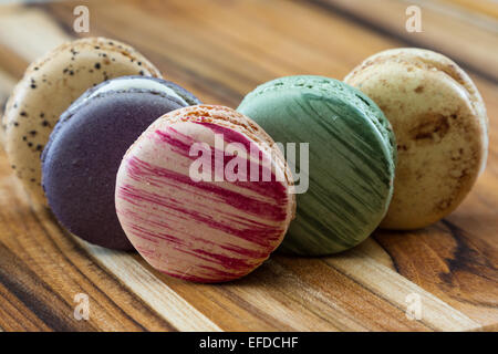 klassische französische Macarons handgefertigt und dekoriert in einer Vielzahl von Farben auf einem Holztisch Stockfoto