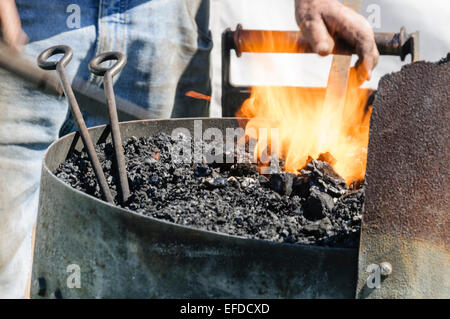 Ein Schmied erwärmt ein Stück Metall in einem Ofen Stockfoto