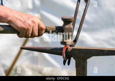 Ein Schmied Hämmer in Form einen glühendes Eisenring auf einem Amboss Stockfoto