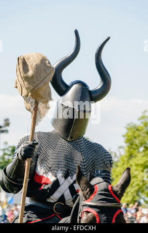 Ein Ritter Kettenhemd und ein gehörnter Helm tragen reitet vorbei auf dem Pferderücken Stockfoto