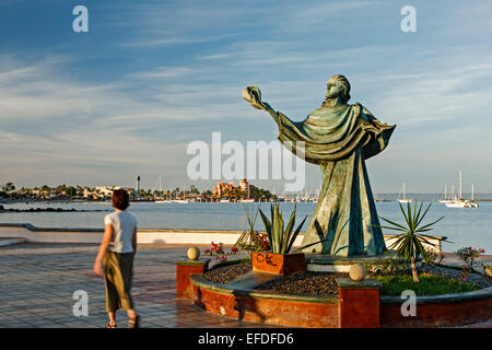 Frau zu Fuß von der Skulptur der Person, die eine Shell und Bucht, Malecon (Strandpromenade), La Paz, Baja California Sur, Mexiko Stockfoto