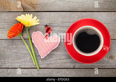 Tasse Kaffee, Herz Spielzeug und Gerbera Blumen auf Holztisch Stockfoto