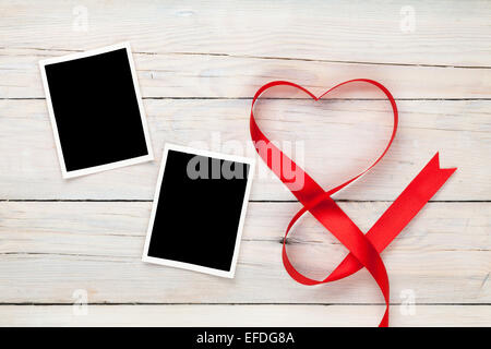 Valentinstag herzförmige rote Schleife und leere Bilderrahmen über Holztisch Hintergrund Stockfoto