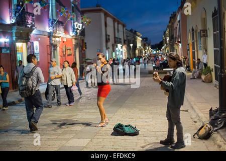 Oaxaca, Mexiko - eine Frau und Mann spielen Violine und Gitarre für Tipps in einer verkehrsberuhigten Straße. Stockfoto