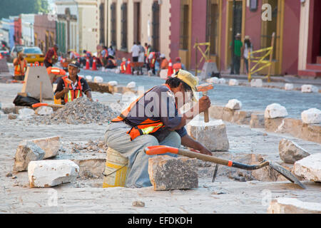 Oaxaca, Mexiko - Arbeitnehmer Gebrauch Hammer und Meißel, eine Straße mit Kopfsteinpflaster wieder aufzubauen. Stockfoto