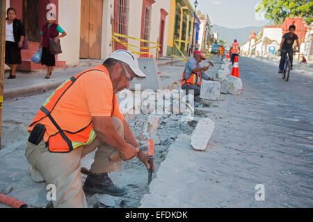 Oaxaca, Mexiko - Arbeitnehmer Gebrauch Hammer und Meißel, eine Straße mit Kopfsteinpflaster wieder aufzubauen. Stockfoto