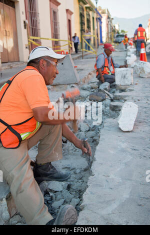 Oaxaca, Mexiko - Arbeitnehmer Gebrauch Hammer und Meißel, eine Straße mit Kopfsteinpflaster wieder aufzubauen. Stockfoto