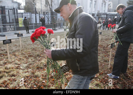Ein Mann legt Blumen in einem der symbolische Kreuze errichtet von Aktivisten in Erinnerung an jene Leute, die vor der russischen Botschaft in Mariupol, getötet wurden. © Sergii Kharchenko/Pacific Press/Alamy Live-Nachrichten Stockfoto
