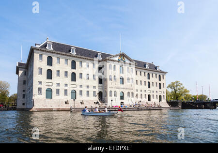 National Maritime Museum (Het Scheepvaartmuseum) in Amsterdam, Holland an einem sonnigen Tag mit blauem Himmel, betrachtet aus dem Kanal Stockfoto