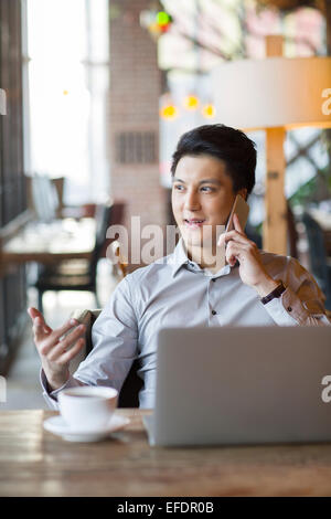 Junger Mann am Telefon im café Stockfoto