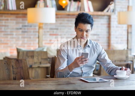 Junger Mann mit Smartphone im café Stockfoto