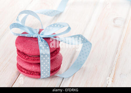 Roten Macarons mit blauem Band auf weißer Holztisch Stockfoto