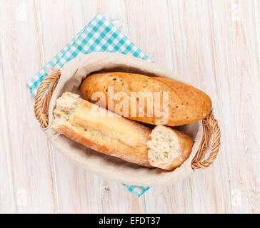 Frisches Baguette in Korb über weißen Holztisch Stockfoto