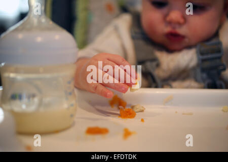 Ein neun Monate altes Baby Mädchen essen zu den Mahlzeiten. Stockfoto