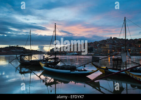 Abend in der Stadt Porto, Portugal. Rabelo traditionellen portugiesischen Fracht Boote mit Weinfässern am Douro-Fluss und Altstadt Stockfoto