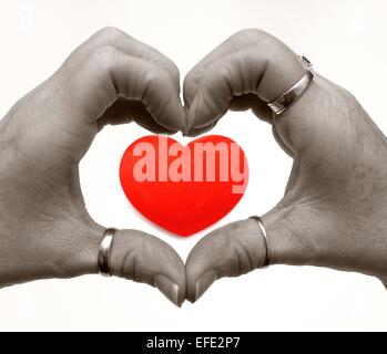 Weibliche Hände in Form eines Herzens mit einem roten Herz Digital hinzugefügt Stockfoto