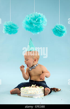 Kleiner Junge essen Kuchen zum ersten Geburtstag Stockfoto