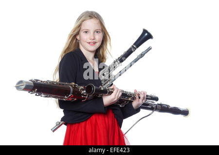 junge blondes Mädchen hält Holzblasinstrumente im Studio vor weißem Hintergrund Stockfoto