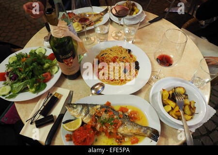Eine Mahlzeit mit ganzer Fisch, eine Schüssel mit Spaghetti und grünem Salat. Stockfoto