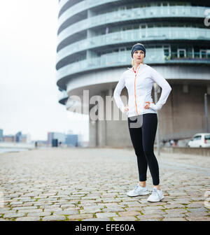 Voller Länge Bild Fit jungen Frau in Sportbekleidung steht auf der Straße wegsehen. Zuversichtlich Sportlerin auf outdoor-training Stockfoto