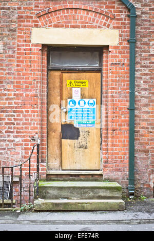 Tür von einem verlassenen Gebäude mit Sicherheitszeichen Stockfoto