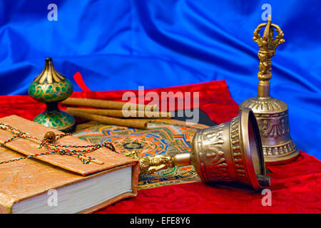 zwei tibetische Ritual Glocke und ein Buch auf blauem Hintergrund Stockfoto