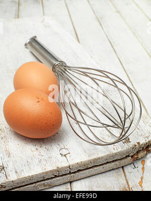 Kit mit frischen Eiern und einem Chrom-Schneebesen Kochen Stockfoto