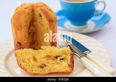 Eine Scheibe des Panettone italienischer Weihnachten Obst Brot Kuchen auf eine Platte für den Nachmittagstee mit einem blauen Teetasse mit Untertasse auf einem Tisch. England Großbritannien Stockfoto