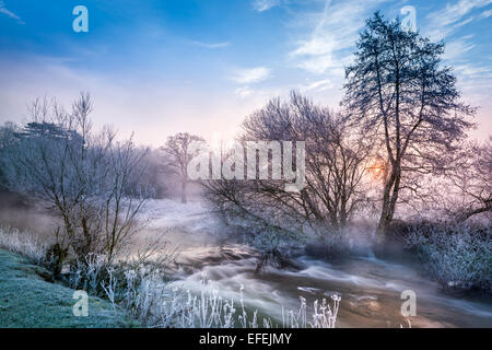 Die Sonne erhebt sich über dem Nebel zu Leuchten ein Wehr-Pool am Fluss Avon in der Nähe von Malmesbury in Wiltshire. Stockfoto