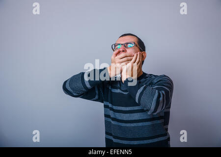 Europäisch anmutende Mann von etwa dreißig schließen die Mund gähnt Händen Stockfoto