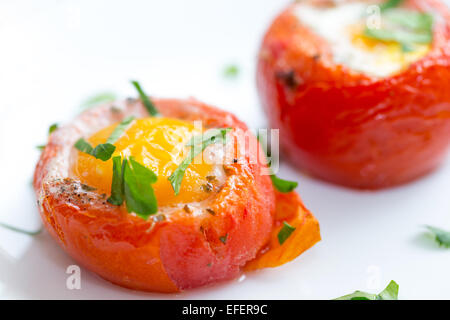 Gebackene, de-entkernten Tomaten gefüllt mit einem Ei und fertig in den Ofen, serviert auf Toast mit einer Petersilie garnieren. Dieses italienische Gericht Stockfoto