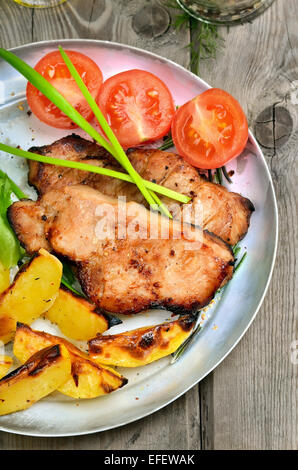 Gebratene Steaks mit Bratkartoffeln und frisches Gemüse auf rustikalen Tisch Stockfoto