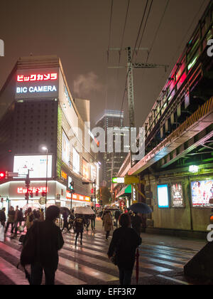 Regnerischen Nachtaufnahme von Menschen über die Straße in der Nähe von der Hochbahn verfolgt in Tokio Stockfoto