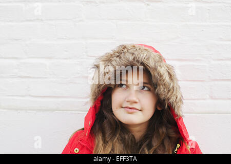 Junges Mädchen im roten Mantel denken und nachschlagen. Stockfoto