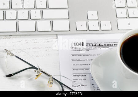 Nahaufnahme des Steuerformulars, Lesebrille, Computertastatur und Kaffee auf weißen Schreibtisch. Konzentrieren Sie sich auf steuerliche Form 1040. Stockfoto