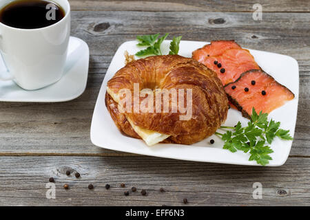 Nahaufnahme von Frühstück mit frisch gebackenen Croissants, mit Ei, kalt geräucherter Lachs, Petersilie auf Seiten- und schwarzen Kaffee am Rost Stockfoto