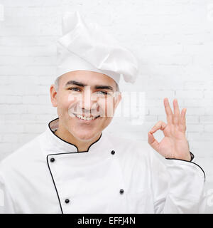 hübscher Chef gekleidet in weiße uniform zeigt ok Sign. Stockfoto