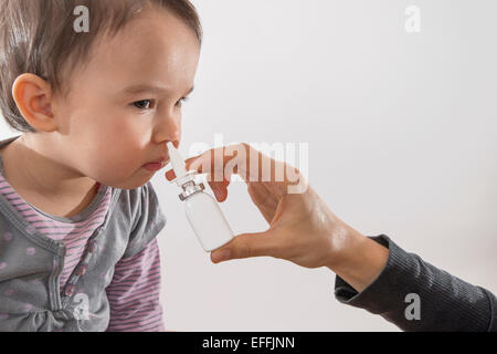 Elternteils Hand eines Mädchens gilt als Nasenspray Stockfoto