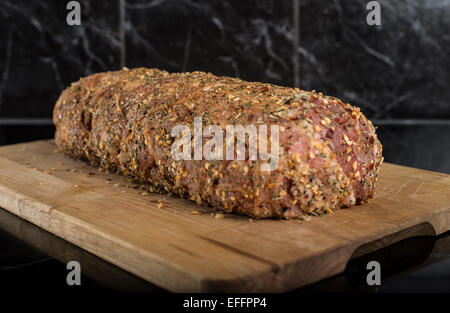 Schweinefilet umhüllt mit Speck und Kräutern auf Holzbrett Stockfoto