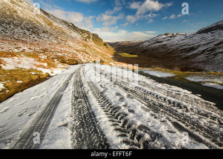 Reifenspuren auf Wrynose Pass im Winter, Lake District, Großbritannien. Stockfoto